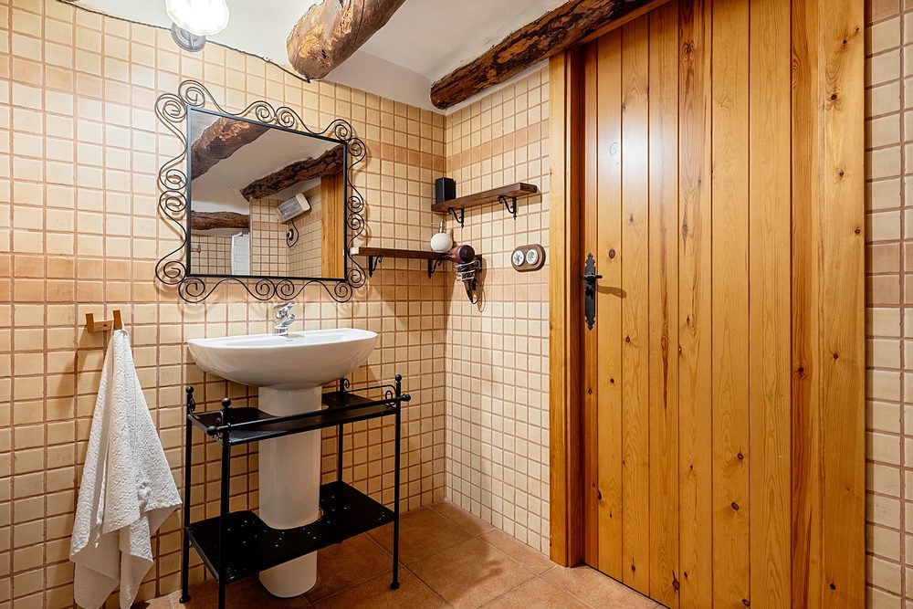 Bany amb lavabo de peu, mirall de ferro i porta de fusta