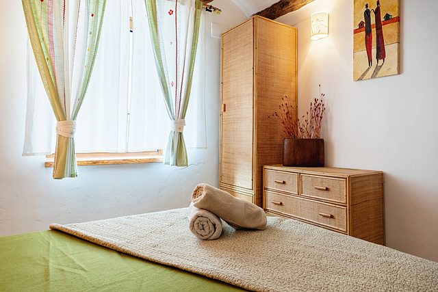 La finestra amb cortines i l’armari de vímet