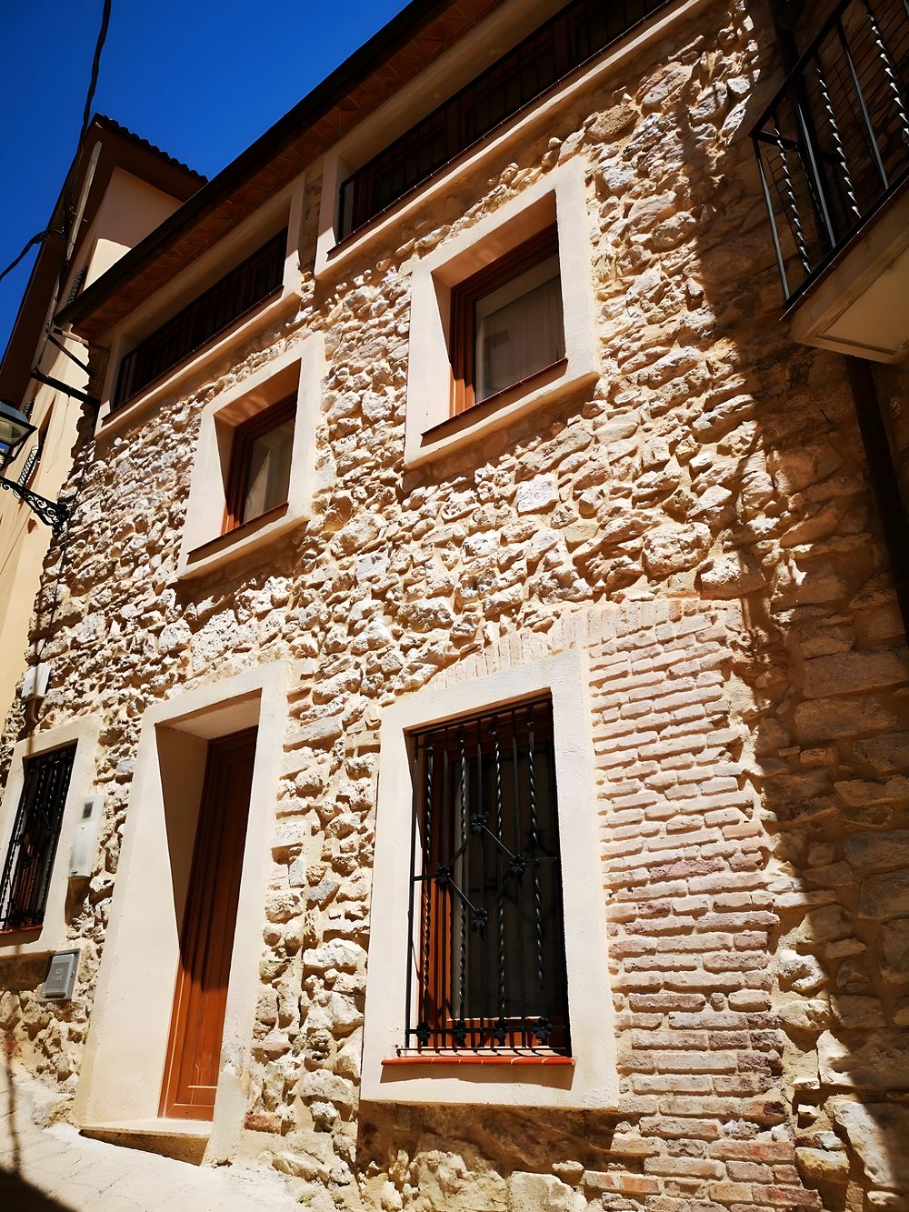 La façana de pedra i maó de la casa, de dia
