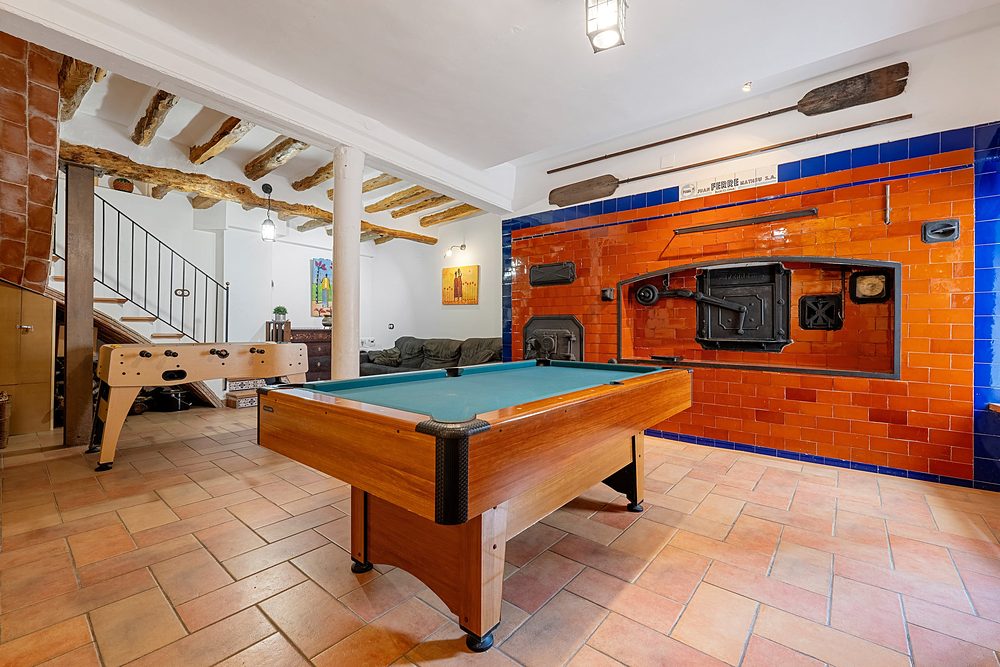 La sala de jocs amb el billar davant del forn antic de rajola