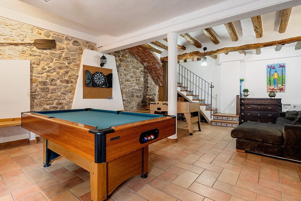 La sala de jocs amb l’arc de pedra i l’escala