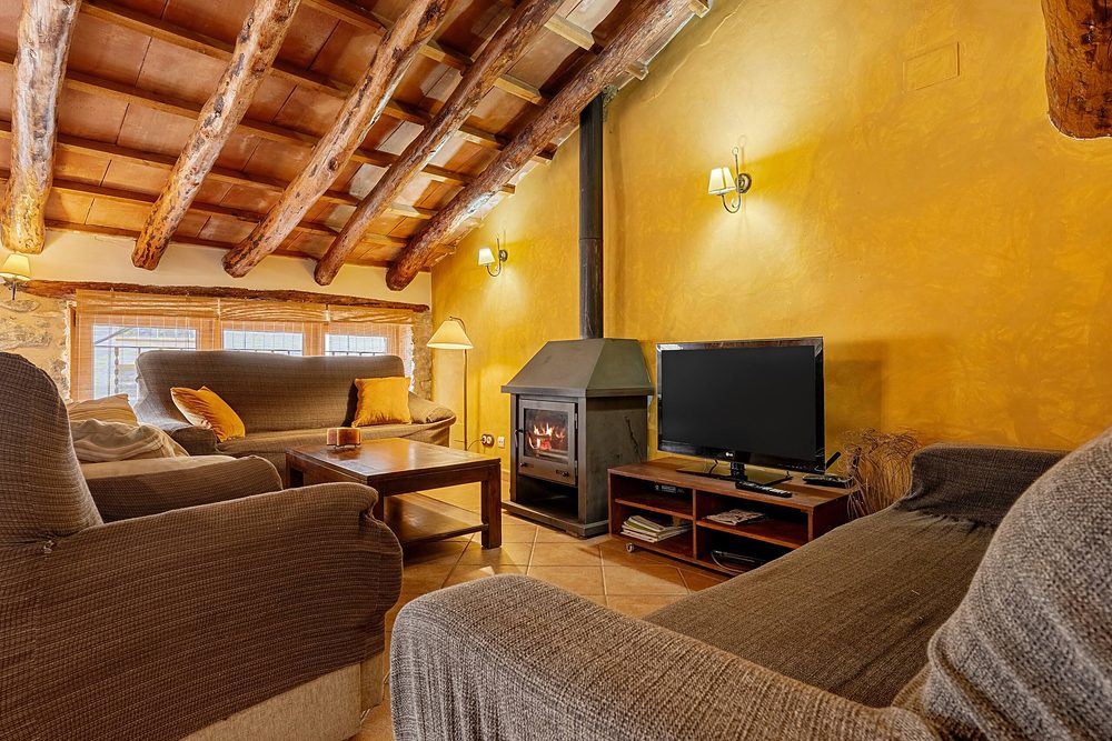 La sala amb l’estufa de llenya, els sofàs i la paret groga