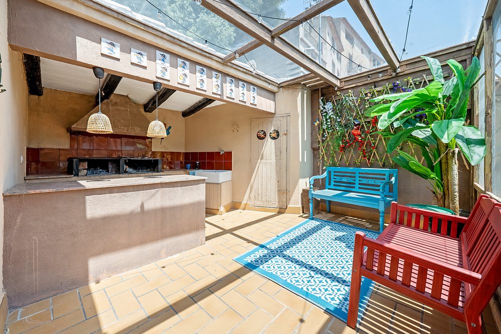 La terrassa coberta amb la barbacoa i els bancs de colors